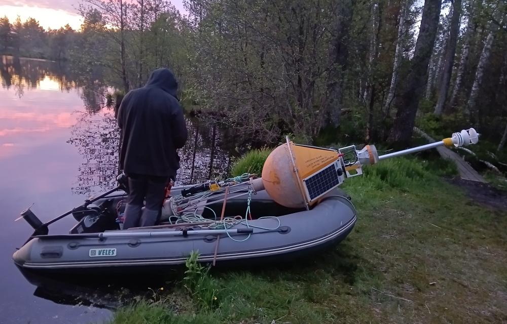 Poi paigaldamine Harku järve, pildil paat, mees ja poi järve kaldal.